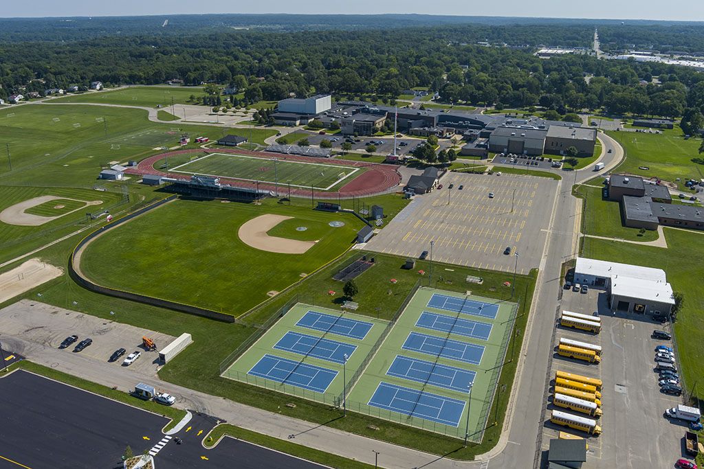 A drone view of tennis courts, baseball diamonds, and football field with track.